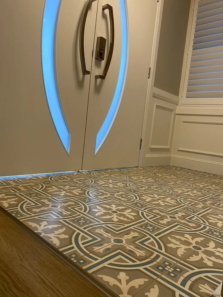 Bespoke double entrance doors with custom curved handles and patterned tile foyer
